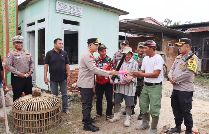 Kombes Pol Jeki Rahmat Mustika menyerahkan bantuan perlengkapan ronda kepada perwakilan warga Perumahan Trenjin, Jalan Cipta Karya, Kelurahan Sialang Munggu, Kecamatan Tuah Madani, Ahad (7/1/2024).