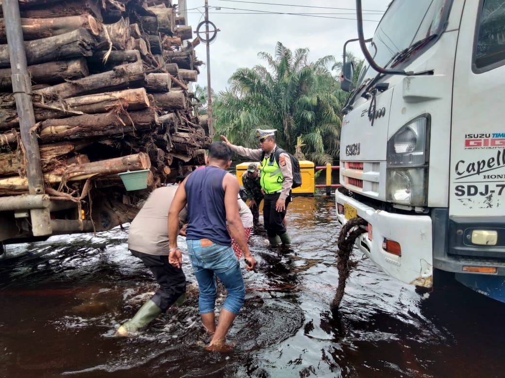 Personil Sat Lantas Polres Pelalawan melakukan evakuasi truk yang terperosok di Jalan Lintas Timur KM 82 Desa Kemang Kecamatan Pangkalan Kuras yang masih direndam banjir, Senin (8/1/2024).