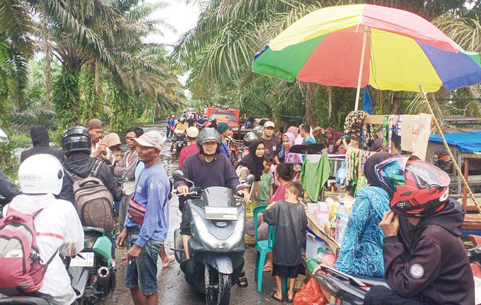 Para pengendara sepeda motor yang ingin menyeberang, antre dan memadati Jalan Dusun Simpang Kualo, Kelurahan Pangkalankerinci Kota, Kecamatan Pangkalankerinci, Kabupaten Pelalawan, Ahad (7/1/2024).