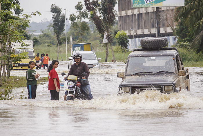 Pengendara roda dua dan roda empat nekat melewati banjir yang merendam Jalan Sembilang, Kecamatan Rumbai, Kamis (11/1/2024).
