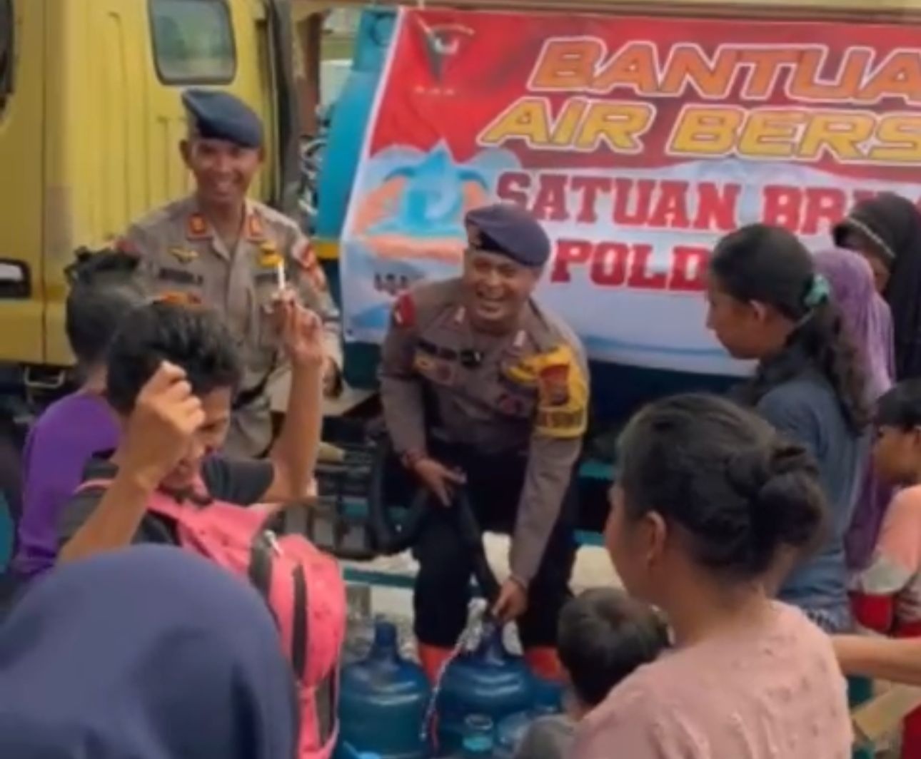 Warga Jalan Nelayan, Kecamatan Rumbai tampak berjoged dan gembira saat Personel Satbrimobda Riau membagikan air bersih untuk masyarakat yang tertimpa banjir, Selasa (17/1/2024).