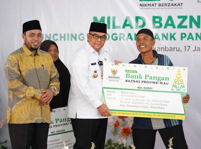 Gubri H Edy Natar Nasution menyerahkan bantuan kepada masyarakat kurang mampu saat milad Baznas Riau, Rabu (17/1/2024).