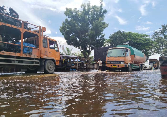 Salah seorang warga memberikan arahan kepada pengendara yang melintasi banjir di jalan lintas Riau-Sumatera Utara, dekat Jembatan Ujung Tanjung, Tanah Putih, Rokan Hilir, Kamis (18/1/2024).