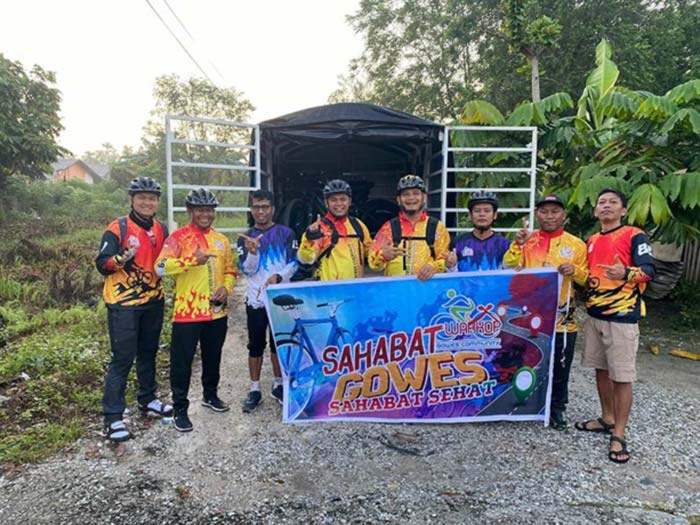 Anggota Warkop Gowes Community membentangkan spanduk saat melaksanakan gowes bersama