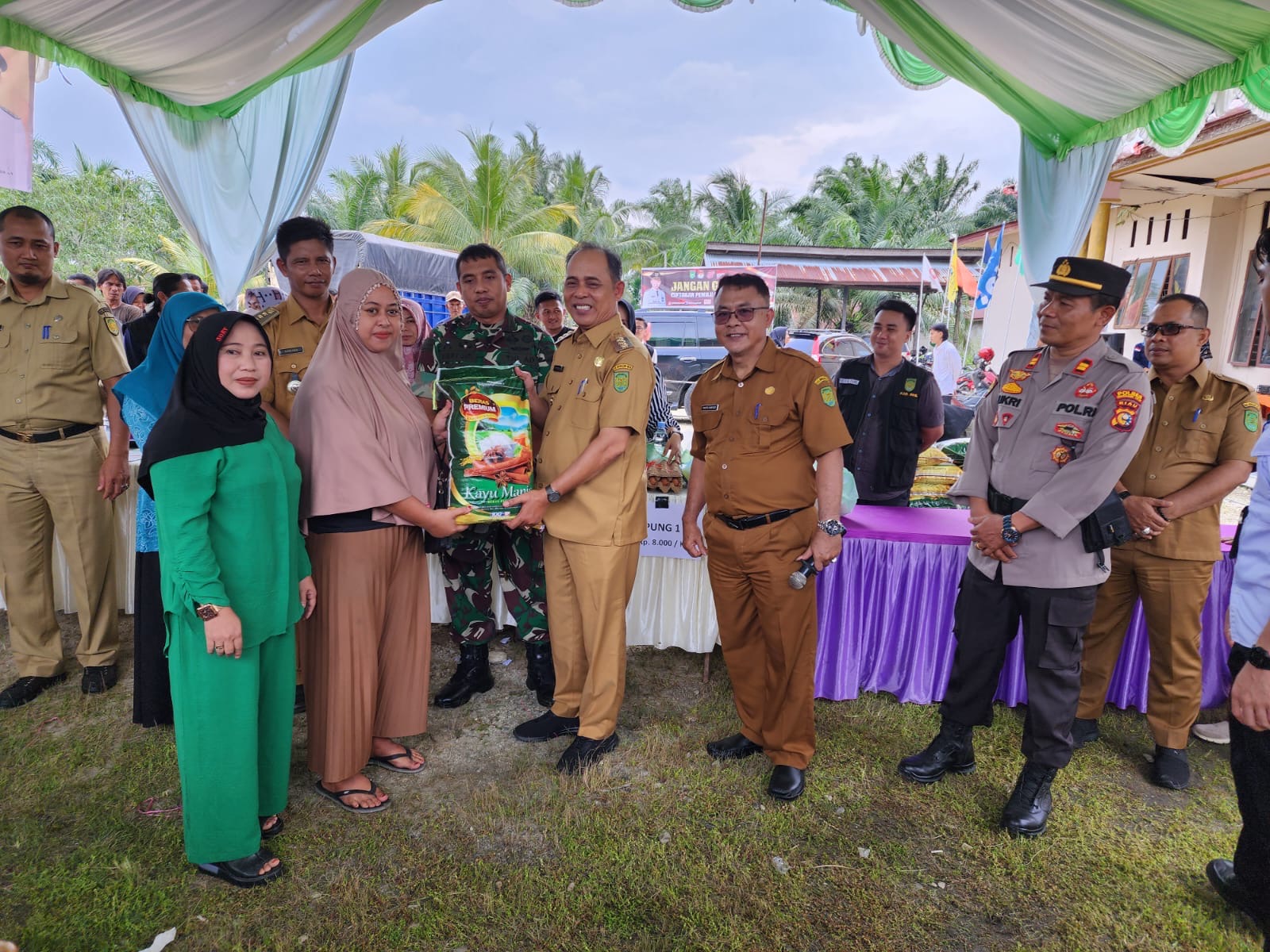 Pj Bupati Inhil H Herman, menyerahkan beras kepada warga yang ikut dalam program pasar murah di Kelurahan Harapan Tani, Kempas, Selasa (23/1/24).