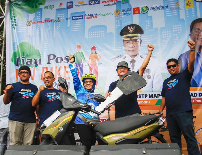 Direktur Utama Riau Pos Ahmad Dardiri dan jajaran foto bersama pemenang hadiah utama Riau Pos Fun Bike Nurmini Sembiring usai penyerahan secara simbolis, Ahad (28/1/2024).