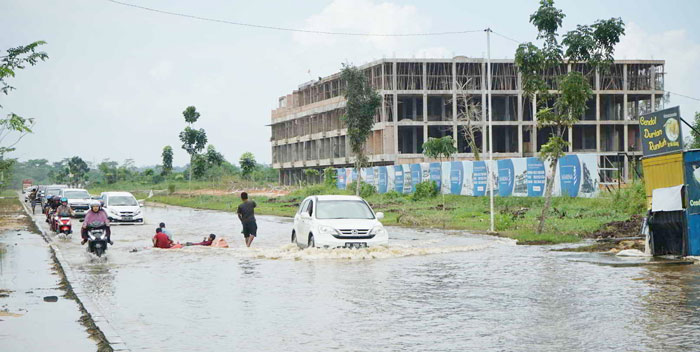 Pengendara melintas di Jalan Jenderal Sudirman ujung yang masih digenangi air akibat luapan Sungai Siak, Senin (29/1/2024).