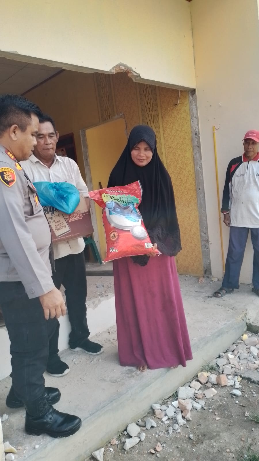 Kapolsek Tambang AKP Marupa Sibarani menyerahkan bantuan kepada warga Desa Tanjung Bungo, Kecamatan Kampa, yang mengalami kerusakan akibat longsor di tepian Sungai Kampar, Selasa (30/1/2024).