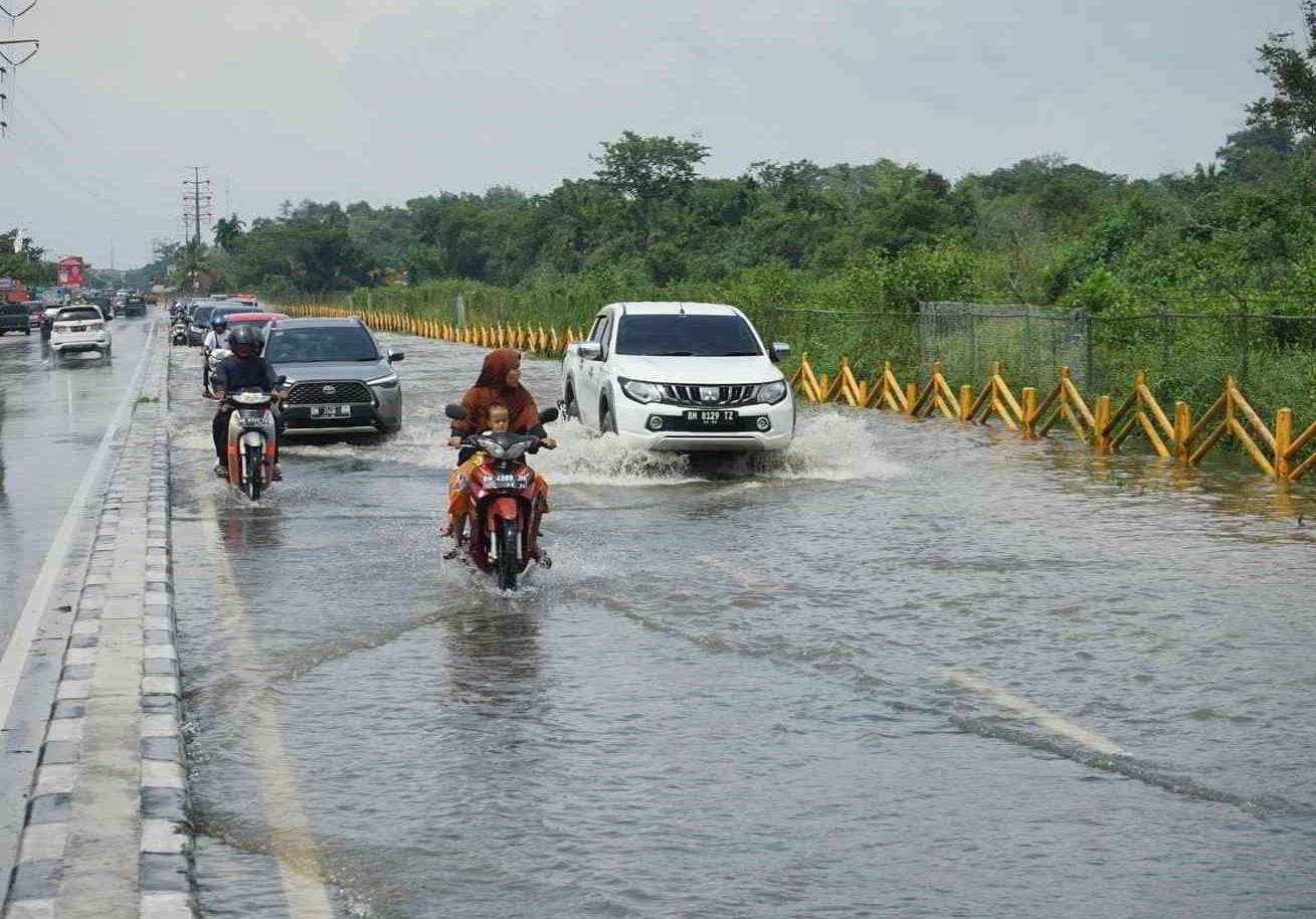 Pengendara melintasi genangan air di Jalan Paus Rumbai Pekanbaru, Senin (5/2/2024).