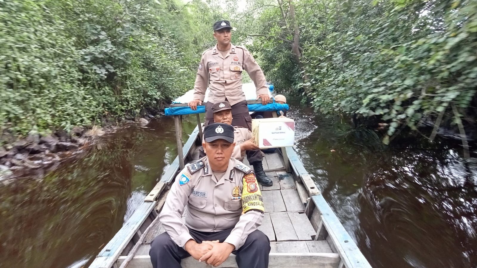 Petugas dari Polsek Sungai Sembilan saat menyusuri sungai yang ada di Kelurahan Bangsal Aceh untuk memberikan bantuan sembako kepada masyarakat, Senin (5/2/2024).