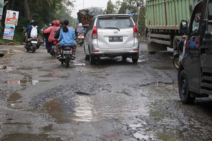 Pengendara melintas di Jalan Kaharuddin Nasution yang rusak parah, Rabu (7/2/2024).