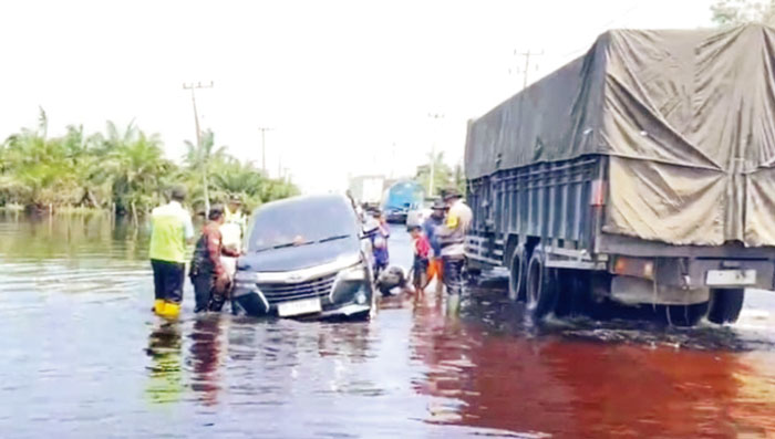 Petugas gabungan mengevakuasi kendaraan roda empat  yang terperosok dalam lubang di Jalan Lintas Timur Km 83 Desa Kemang, Kacamatan Pangkalan Kuras, Kabupaten Pelalawan, Ahad (11/2/2024).