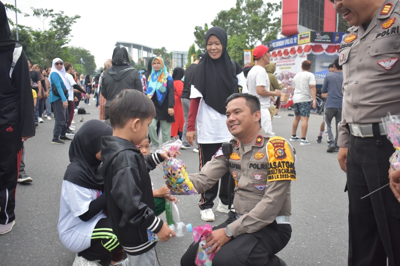 Kasat Lantas Polresta Pekanbaru Kompol Alvin Agung Wibawa saat membagika souvenir kepada anak-anak yang berada di area Car Free Day, Ahad (11/2/2024).