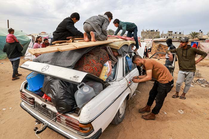 Seorang pria mengikat tali ke dalam kendaraan yang penuh dengan barang-barang ketika anggota keluarga Palestina melarikan diri dari Rafah di Jalur Gaza selatan, Selasa (13/2/2024).