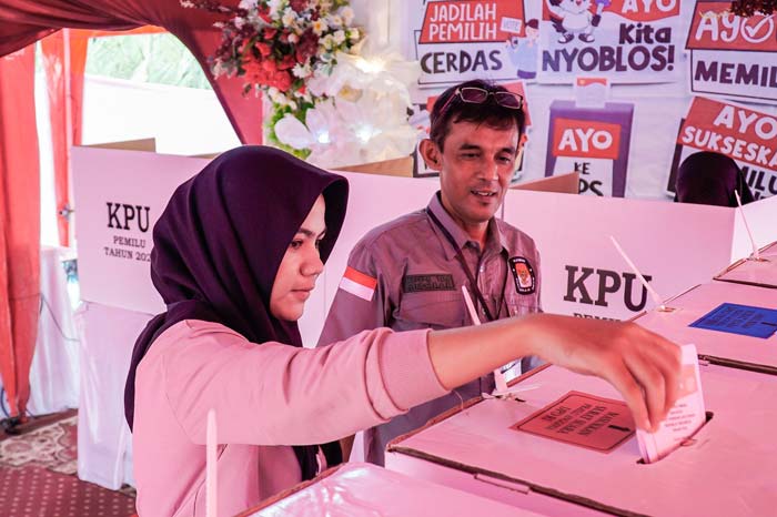 Seorang warga didampingi petugas KPPS memasukkan surat suara Pemilu 2024 ke kotak suara di TPS 106, Kelurahan Sidomulyo Barat, Kecamatan Tuah Madani, Pekanbaru