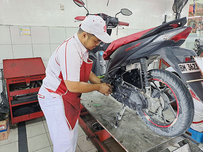 Mekanik Honda melakukan service sepeda motor Honda milik konsumen, baru-baru ini.