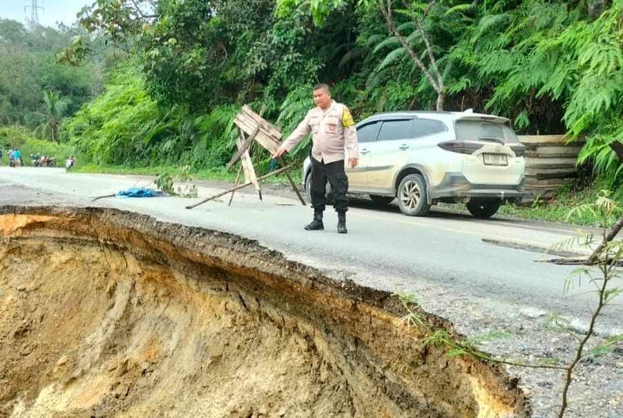 Anggota polisi sedang menunjuk longsor di bahu Jalan Lintas Telukkuantan-Sumbar, tepatnya di Kawasan Bukit Betabuh, Ahad (18/2/2024).