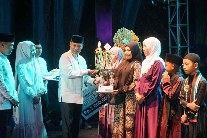 Pj Wako Pekanbaru Muflihun menye&shy;rahkan hadiah dan piala kepada pemenang kasidah dan pildacil saat kegiatan Gema Isra Mikraj 1445 H di Jalan Cut Nyak Dhien, Sabtu (17/2/2024) malam.