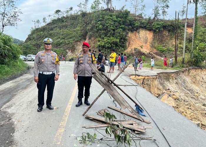 Kasatlantas Polres Kuansing AKP Boy Setiawan dan Kasatreskrim AKP Linter meninjau jalan longsor di kawasan Bukit Betabuh, Ahad (18/2/2024).