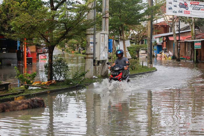 Pengendara sepeda motor melewati genangan banjir yang merendam jalan utama Kompleks Perumahan Griya Sidomulyo, Kelurahan Perhentian Marpoyan, Kecamatan Marpoyan Damai, Kamis (22/2/2024).