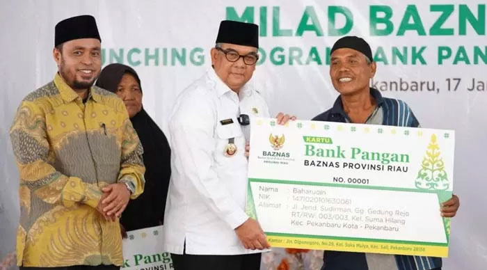 Gubri H Edy Natar Nasution menyerahkan bantuan kepada masyarakat kurang mampu saat milad Baznas Riau, Rabu (17/1/2024).