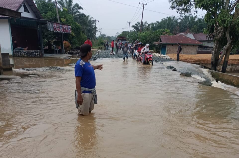 Warga mengarahkan pengendara kendaraan  ketika melintas di Jalan Lintas Rengat -Tembilahan di Desa Sungai Raya, Rabu (28/2/2024).