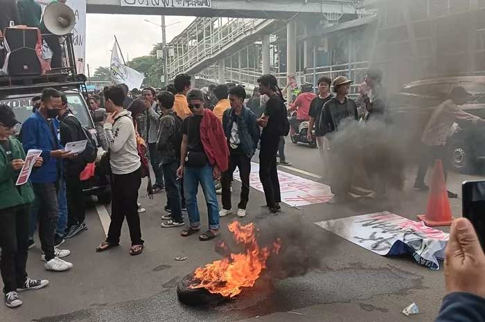 Ratusan mahasiswa melakukan aksi bakar ban dekat halte UNJ.