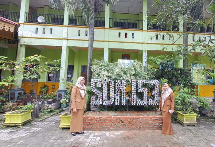 memperlihatkan papan nama sekolah dari ecobrick yaitu susunan botol bekas berisi sampah plastik, Senin, (4/3/2024).