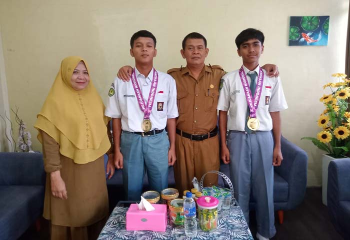 Kepala SMAN 3 Siak Hulu Agus Sutiyono SH didampingi Wakil Kesiswaan Asmaneli SPd foto bersama dua siswa peraih medali emas taekwondo nasional.