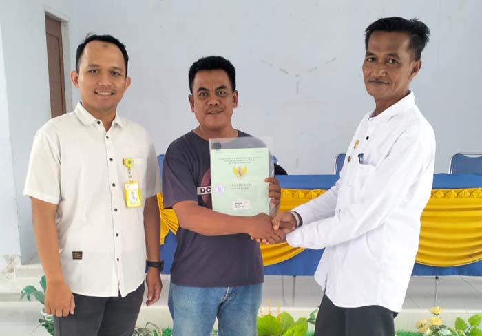 Pj Kades Danau Baru Fitra Wirman (kanan) didampingi Wakil Ketua Fisik PTSL 2024 pada Kantah Inhu Septrian Nurul Fajri saat menyerahkan sertifikat tanah kepada salah seorang warga Desa Danau Baru.
