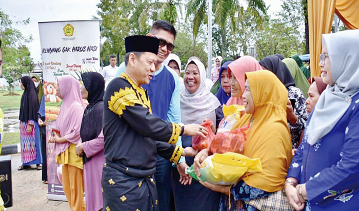 Pj Bupati Kampar Hambali menyerahkan secara simbolis paket sembako saat menggelar pasar murah di Taman Kota Bangkinang, Jumat (8/3/2024).