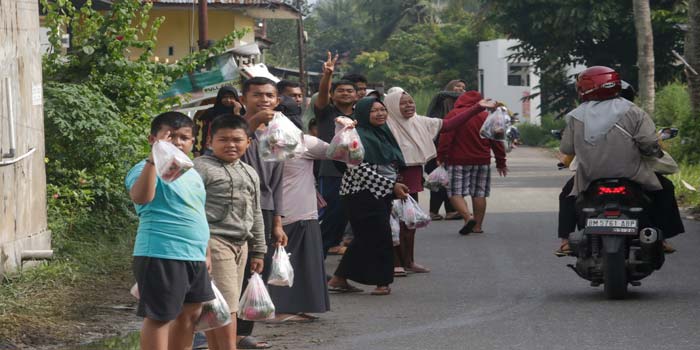 Warga sekitar TPU Sukaharjo di Jalan Kartama, Kecamatan Marpoyan Damai menawarkan air berisi bunga kepada peziarah yang lewat, Senin (11/3/2024).