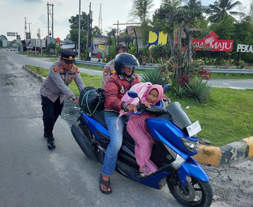 Kapolsek Tambang AKP Marupa Sibarani mendorong sepeda motor pemudik yang mogok  di depan pintu Tol Pekanbaru- Bangkinang, Desa Sungai Pinang Kecamatan Tambang Kabupaten Kampar, Sabtu (13/4/2024).