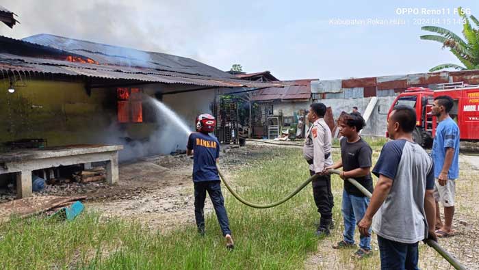 Petugas Damkar Ujung Batu dibantu TNI, Polisi dan masyarakat berjibaku memadamkan kobaran api yang membakar bagian dapur Rumah Makan Bang Ali Kelurahan Ujung Batu,  Senin (15/4/2024).