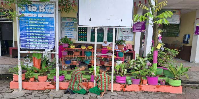 Murid SDN 25 Pekanbaru sedang merawat tanaman, beberapa waktu lalu. Murid memanfaatkan barang bekas menjadi pot bunga untuk menjaga lingkungan.