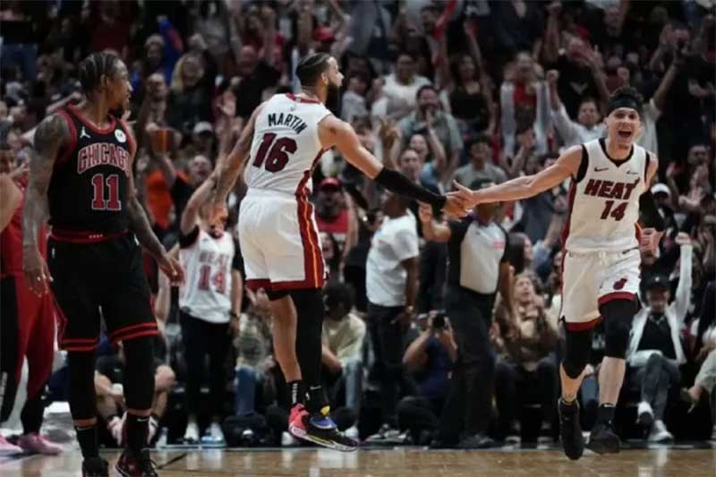 Pemain Miami Heat Tyler Herro (kanan) merayakan tripoin yang dibuatnya bersama Caleb Martin (tengah) saat timnya melawan Chicago Bulls pada babak play-in di Kaseya Center Miami, Florida.