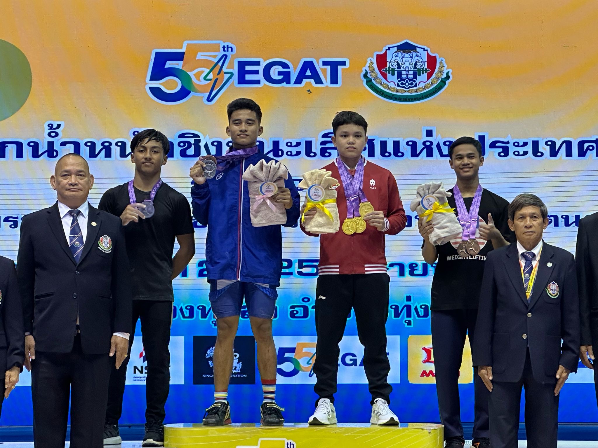 Lifter muda Riau Kevin Andrian Ramadhan (jaket merah) berhasil meraih 3 emas dalam kejuaraan angkat besi EGAT King&rsquo;s Cup 2024 di Thailand pada Ahad (21/4/2024).