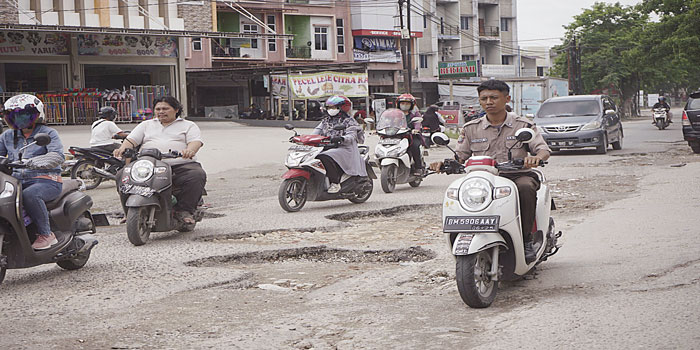 Pengendara menghindari lubang-lubang yang banyak terdapat di Jalan Darma Bakti, Kecamatan Payung Sekaki, Senin (29/4/2024).