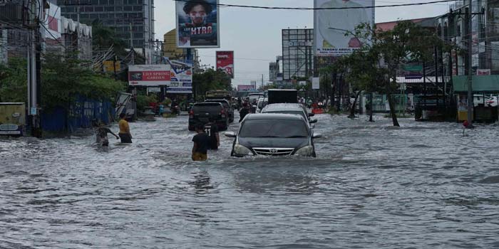 Kendaraan roda empat menerobos banjir yang menggenangi Jalan Riau, Pekanbaru, Rabu (1/5/2024). Tampak anak-anak warga setempat ikut memandu pengemudi yang melintasi jalan tersebut.