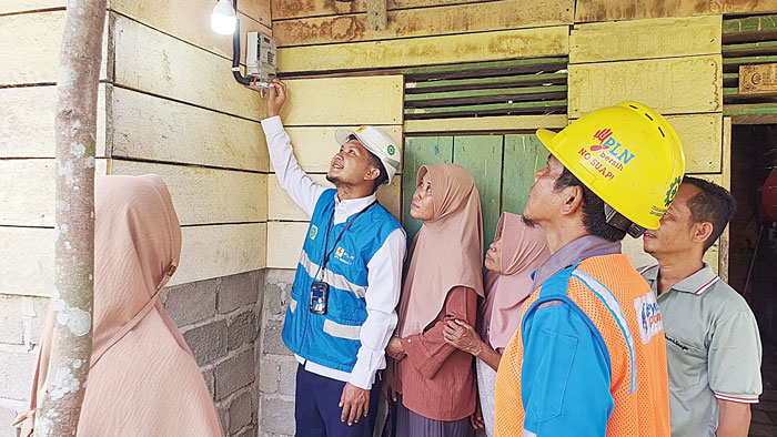 Petugas PLN UP3 Rengat disaksikan warga dan pemilik rumah saat pengaktifan pemakaian listrik melalui program PLN masuk dusun di Desa Pauh Ranap, Kecamatan Peranap, Selasa (7/5/2024).