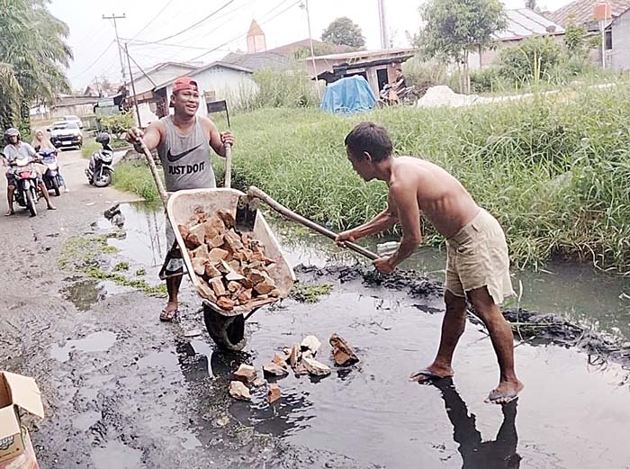 Warga Jalan Rokan secara swadaya melakukan gotong royong memperbaiki jalan yang rusak dengan cara menimbun dengan sisa bahan bangunan, Selasa (7/5/2024).