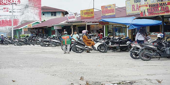 Juru parkir  (jukir) membantu pengendara yang akan keluar dari area parkir di dalam Pasar Tradisional Cik Puan, Jalan Tuanku Tambusai, Senin (13/5/2024).