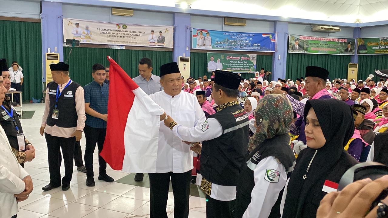 Pj Gubri SF Hariyanto menyerahkan bendera merah putih kepada petugas haji kloter 3 BTH di embarkasi Batam, Selasa (14/5/2024).