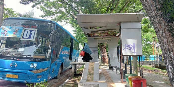 Salah seorang calon penumpang bus Trans Metro Pekanbaru memasuki bus yang berhenti di halte yang kondisinya mulai rusak di Jalan Jenderal Sudirman, Kamis (15/5/2024)