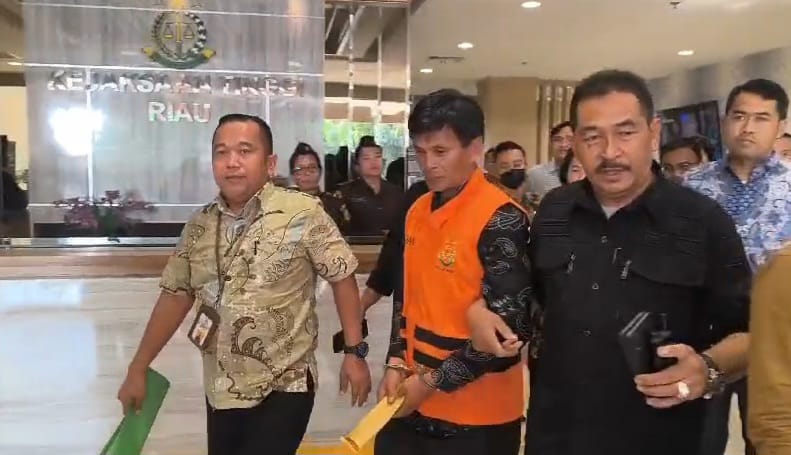 Kasi Penkum dan Humas Kejati Riau Bambang Heripurwanto (kiri) ikut menggiring tersangka Jalunis (rompi oren) yang akan dititipkan di Rutan Kelas I Pekanbaru pada Jumat (17/5/2024). &nbsp;
