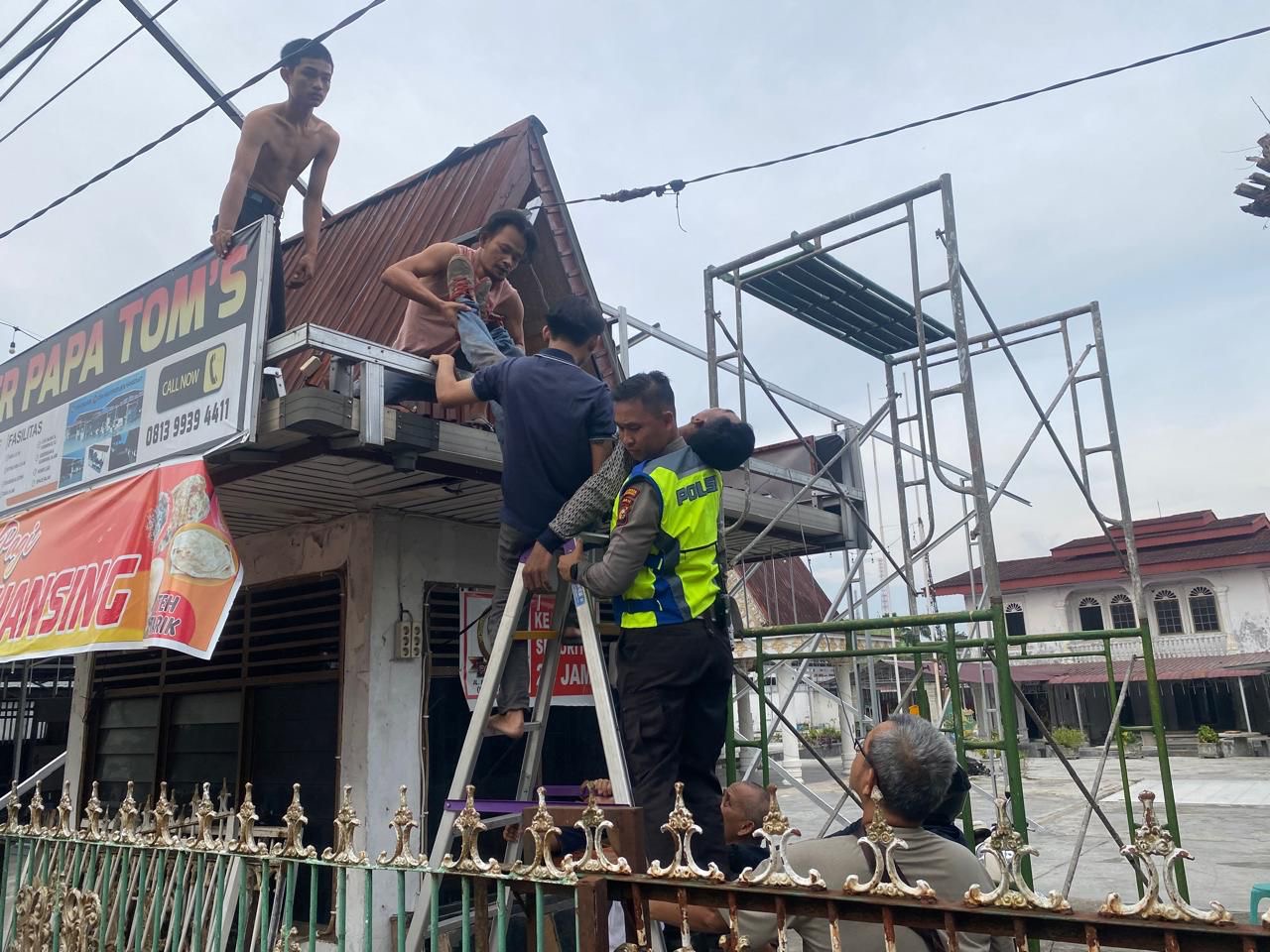 Anggota Satlantas Polresta Pekanbaru Bripka Erry Gunawan Sembiring saat membantu pekerja kanopi yang mengalami kecelakaan kerja, Selasa (21/5/2024).