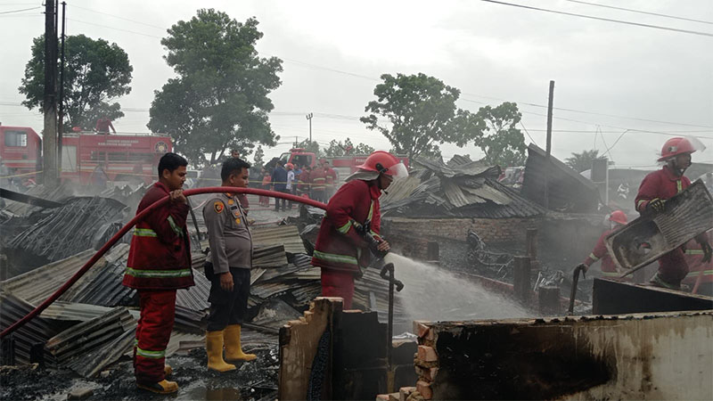 Kapolsek Tambang AKP Marupa Sibarani dan personel Damkar memadamkan api yang membakar enam kios di Rimbo Panjang Kecamatan, Kabupaten Kampar hangus terbakar, Rabu (22/5/2024).