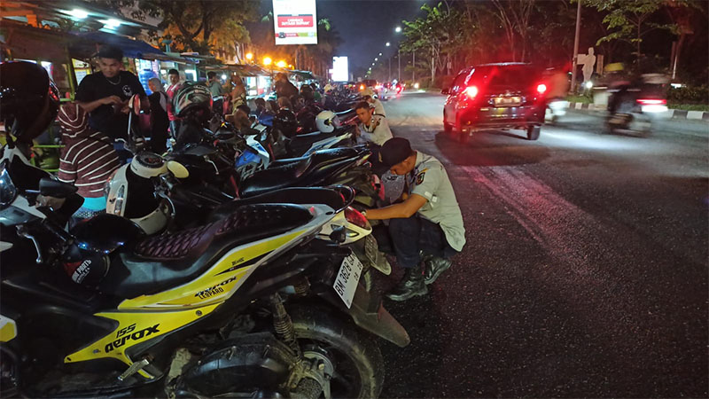 Petugas Dishub tengah mengembosi kendaraan roda dua yang parkir di pinggir jalan Tuanku Tambusai, tepatnya disamping Mal SKA Pekanbaru pada Sabtu (25/5/2024) malam.