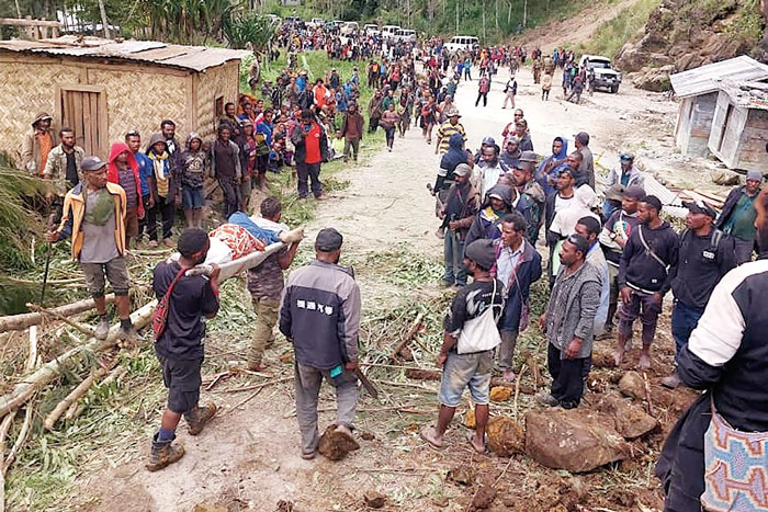 Penduduk setempat membawa seseorang dengan tandu dari lokasi tanah longsor di Desa Yambali wilayah Maip Mulitaka, Provinsi Enga, Papua Nugini, Ahad (26/5/2024).