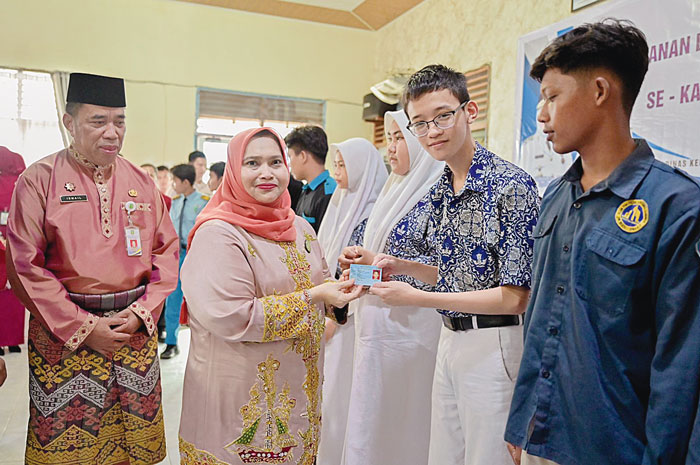 Bupati Bengkalis Kasmarni menyerahkan KTP-el dan KIA secara simbolis kepada siswa-siswi di SMAN 1 Bengkalis dalam rangka layanan kependudukan oleh Disdukcapil Bengkalis, Selasa (28/5/2024).